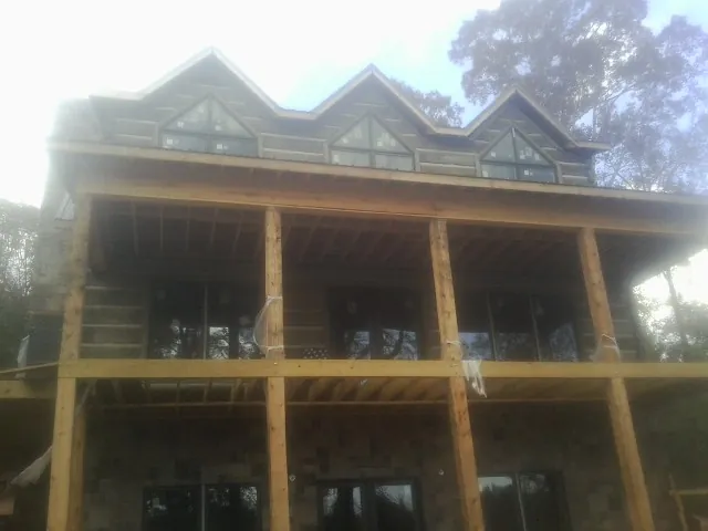 Dormers and porch framing on a large log home under construction — Roof Coating work by our crew in Nortonville