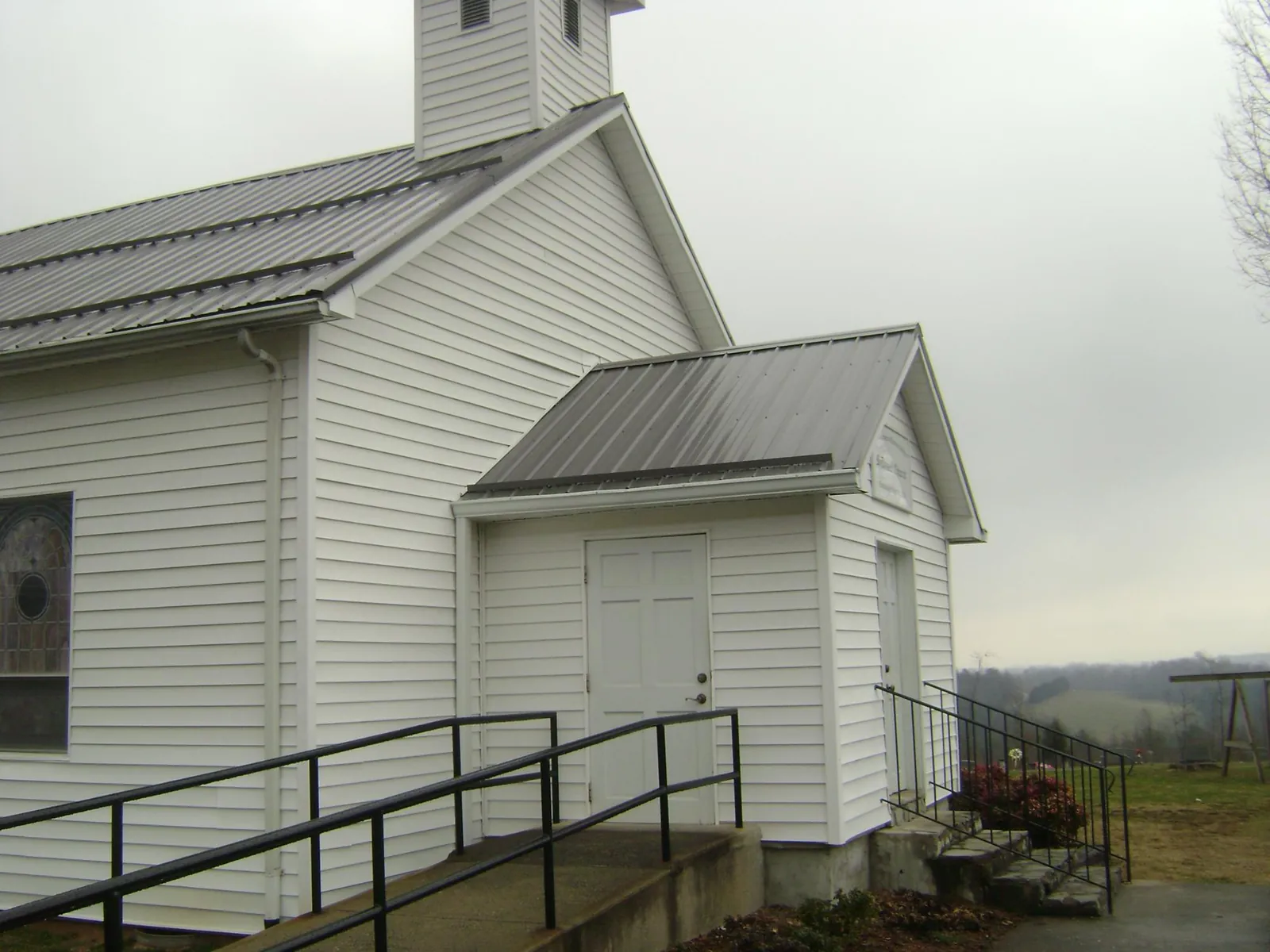 Gray metal roof on a white clapboard church with a steeple in Nortonville