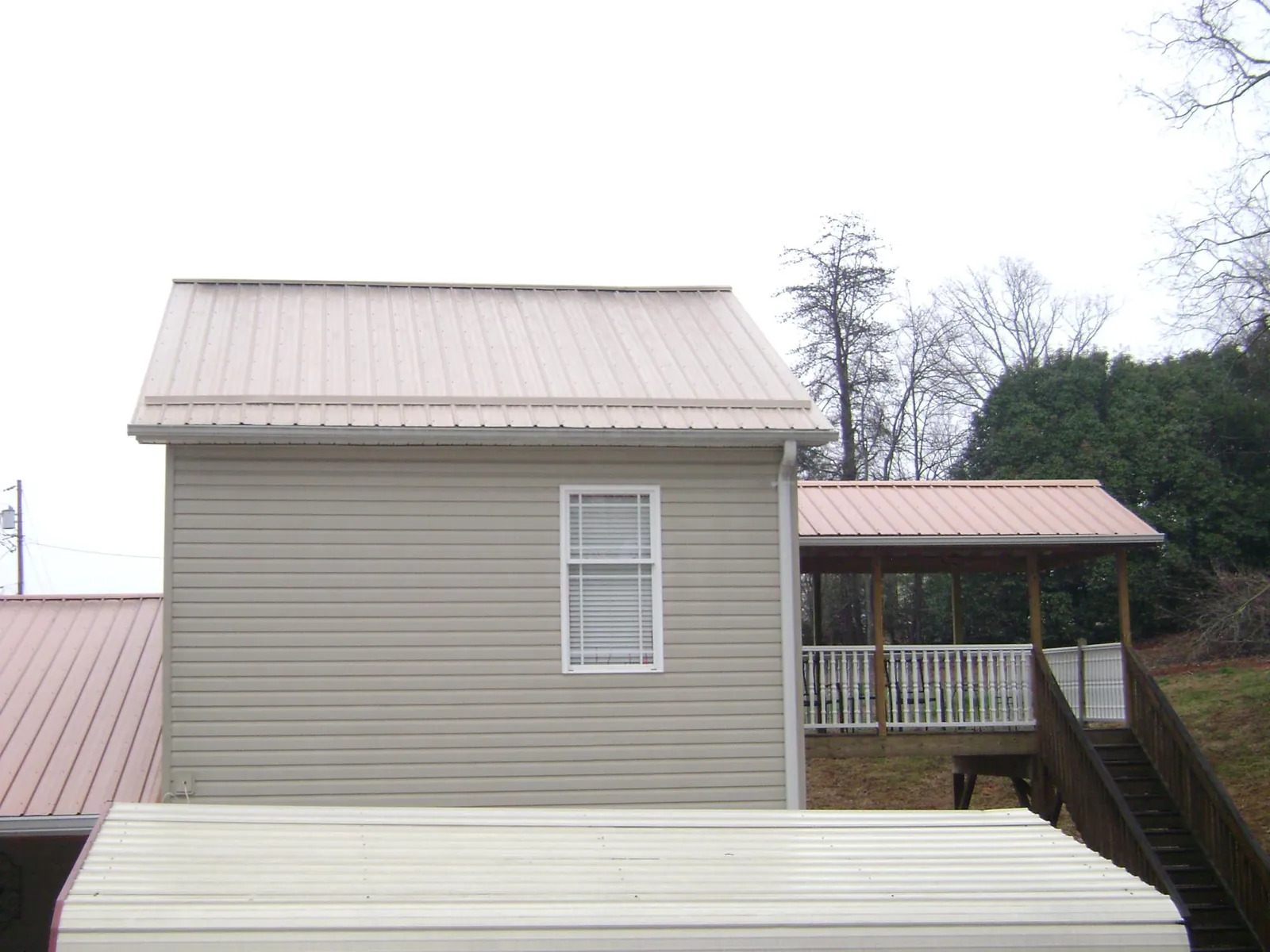 Tan metal roofs on a two story addition and attached porch, from a Roof Replacement job in Nortonville