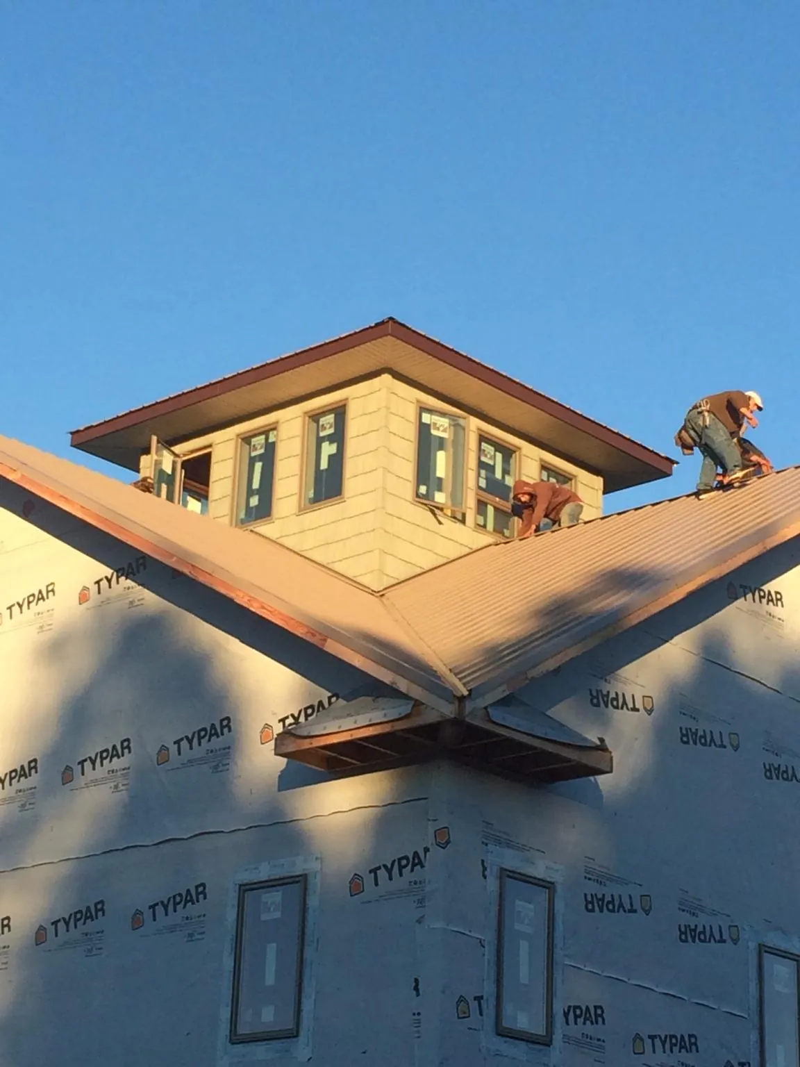 Roofers working around a rooftop cupola on a new metal roof at sunset — Roof Waterproofing in Nortonville by Roofing Brothers